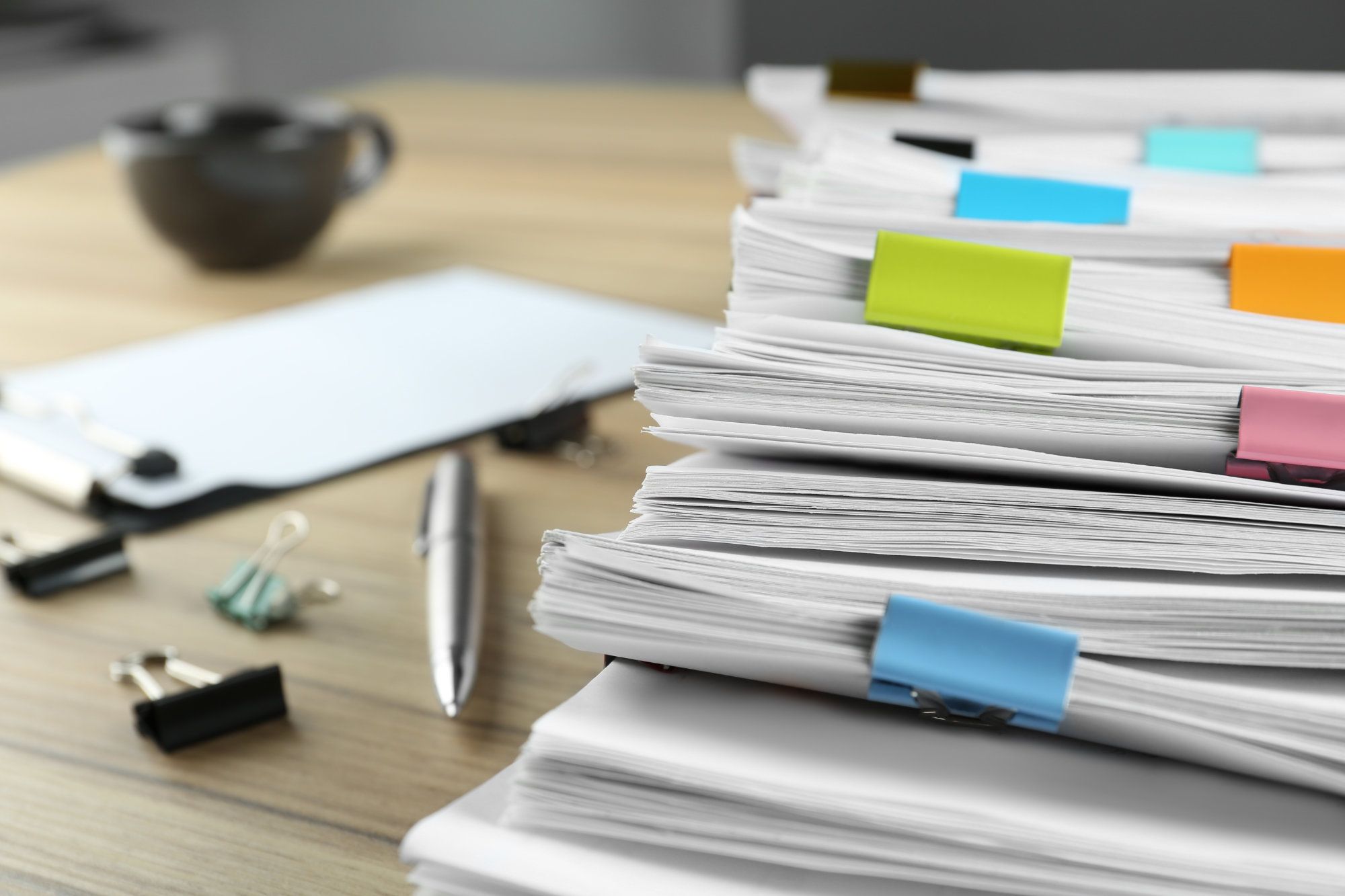 Stack of standards and compliance documents with coloured tabs on a desk